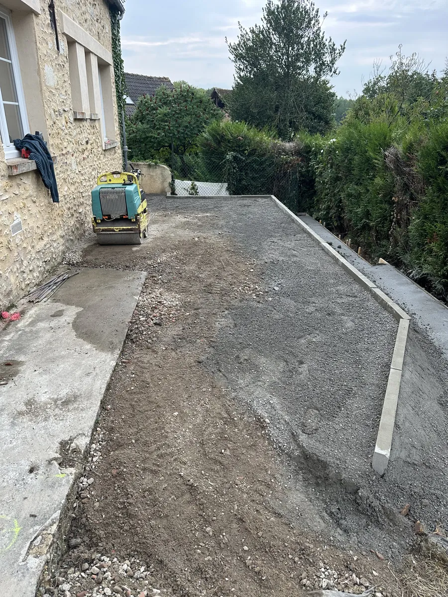 Fond de terrasse en grave compactée le long d'une maison en pierre