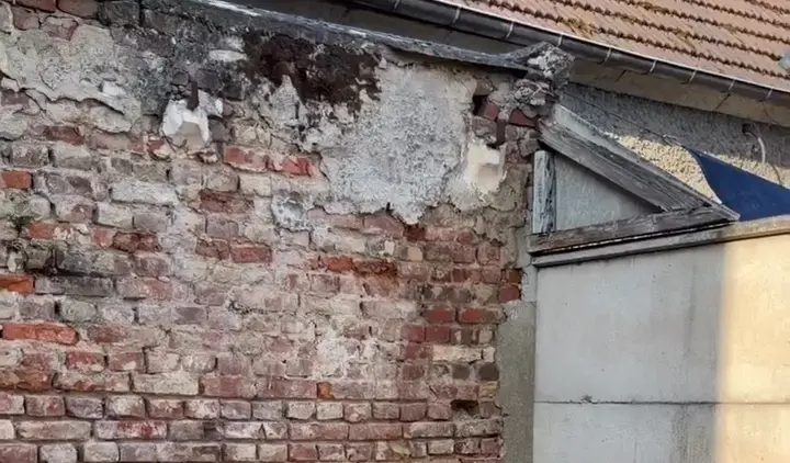Le mur de briques avant les travaux, couvert d'un vieil enduit