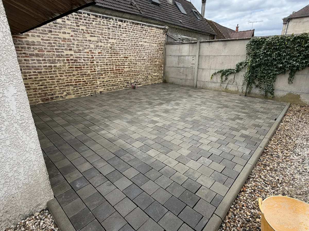 Cour en pavés gris au pied du mur de briques, entre deux murs