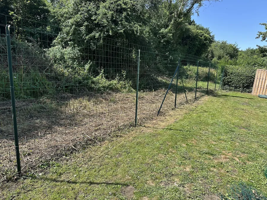 Clôture en grillage tendu entre des poteaux le long d'un terrain
