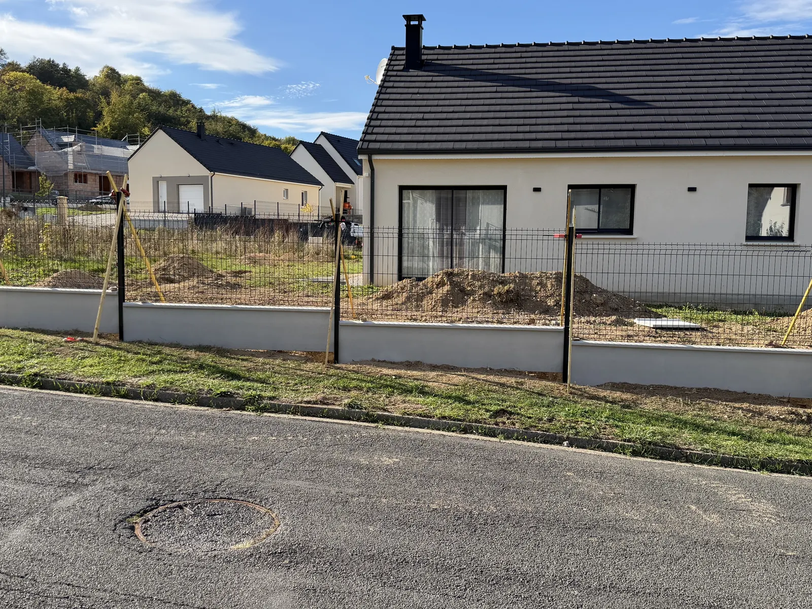 Clôture en panneaux rigides sur plaques de soubassement devant des pavillons neufs