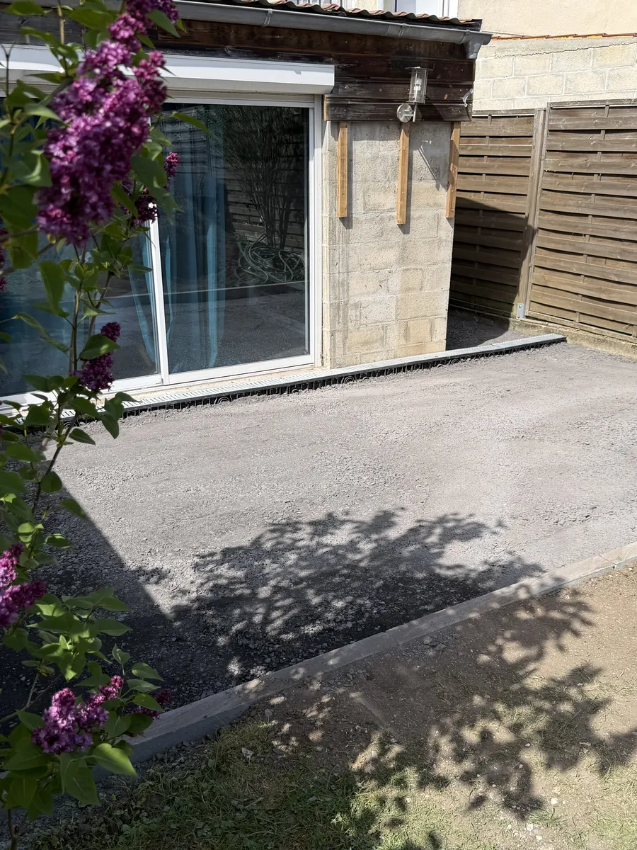 Fond de terrasse en grave réglé et bordé au pied d'une maison