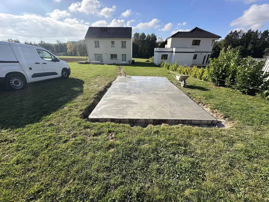 Dalle béton coulée au fond d'un jardin pour recevoir un abri