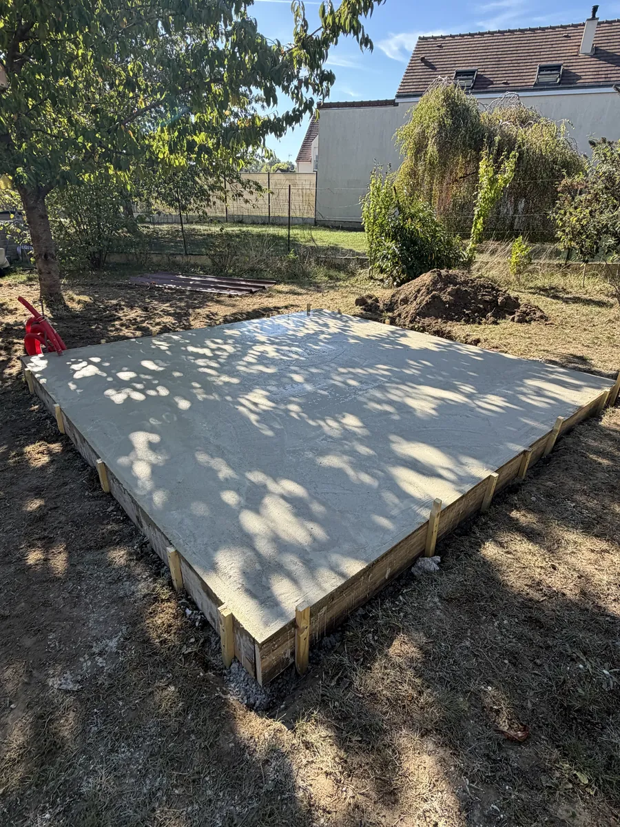 Dalle béton coulée dans son coffrage au fond d'un jardin, pour recevoir un carport
