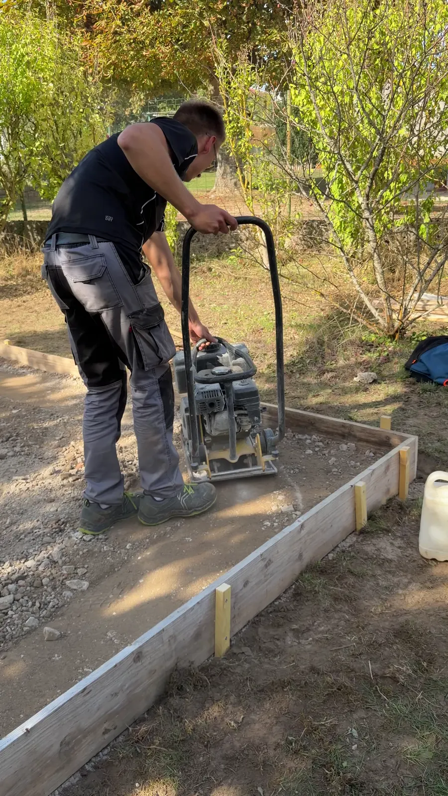 Compactage du lit de cailloux à la plaque vibrante, dans le coffrage d'une dalle