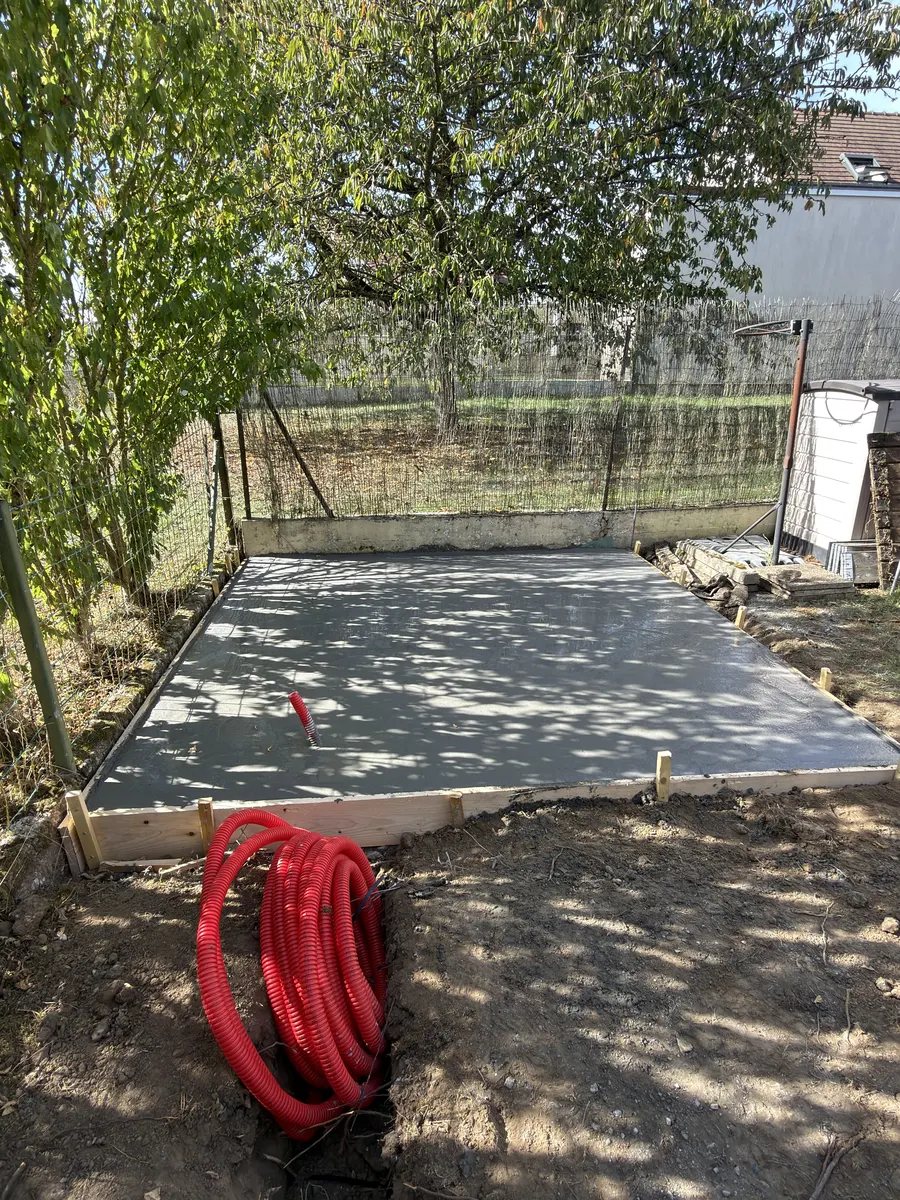 Dalle béton terminée dans un jardin, gaine rouge en attente