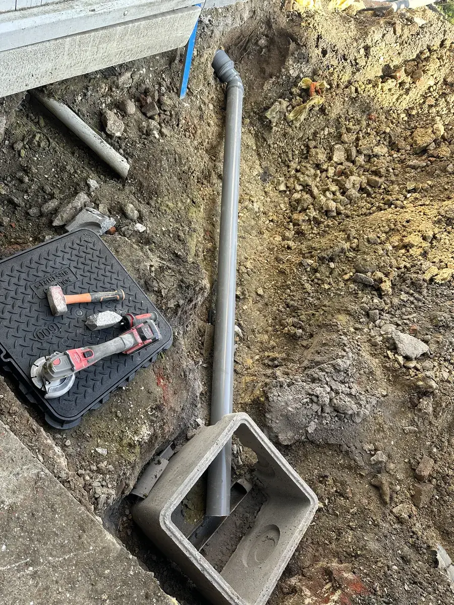 Tuyau de descente raccordé à un regard en béton dans une tranchée ouverte