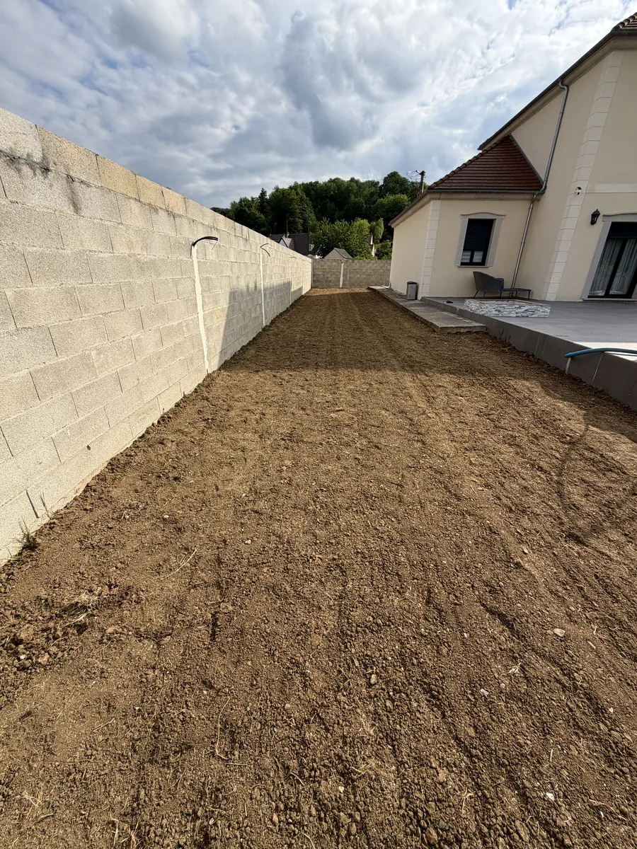 Bande de terre affinée et égalisée le long d'une maison, prête pour le semis