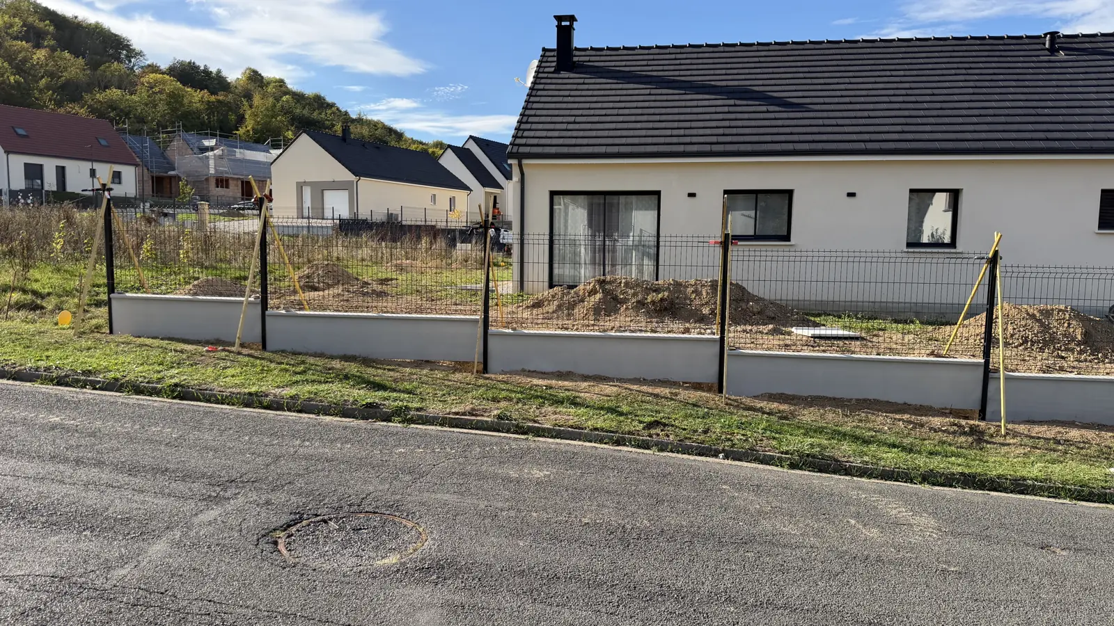 Clôture en panneaux rigides sur soubassement devant des pavillons neufs