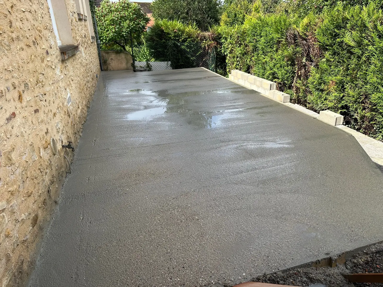 Dalle béton de 40 m² fraîchement coulée le long d'un mur