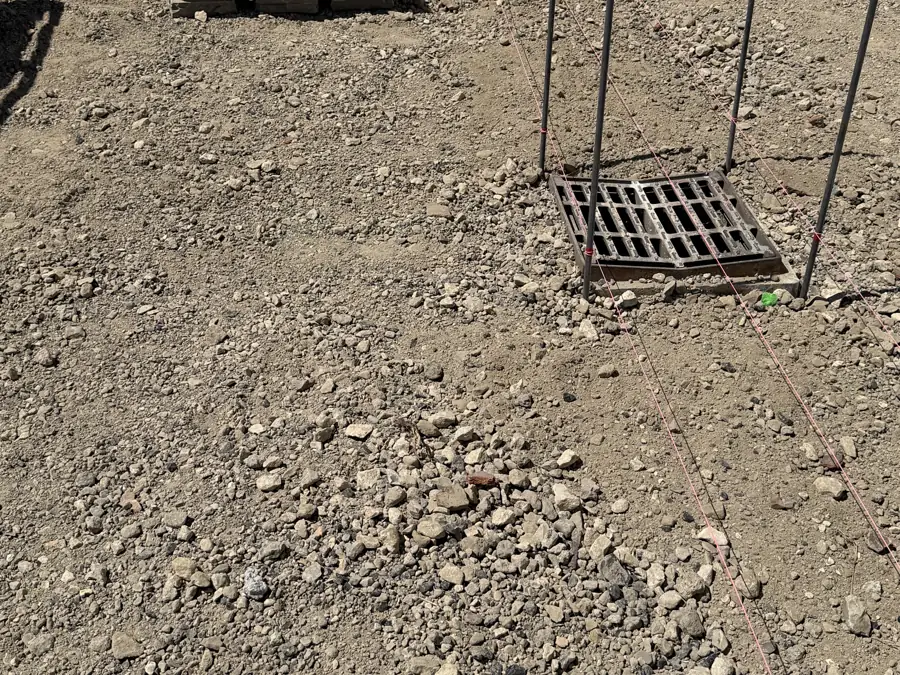 Grille rabaissée dans une cour, des pavés posés en caniveau pour y mener l'eau