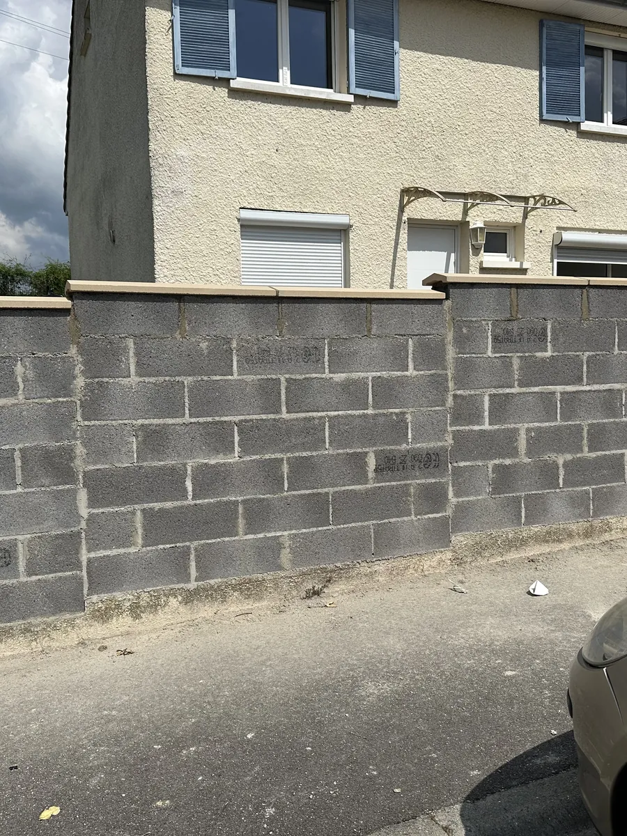 Mur de clôture en parpaings monté devant une maison