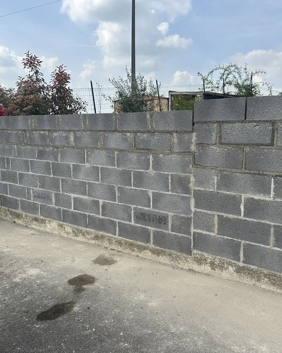 Mur de clôture en parpaings monté le long d'un trottoir