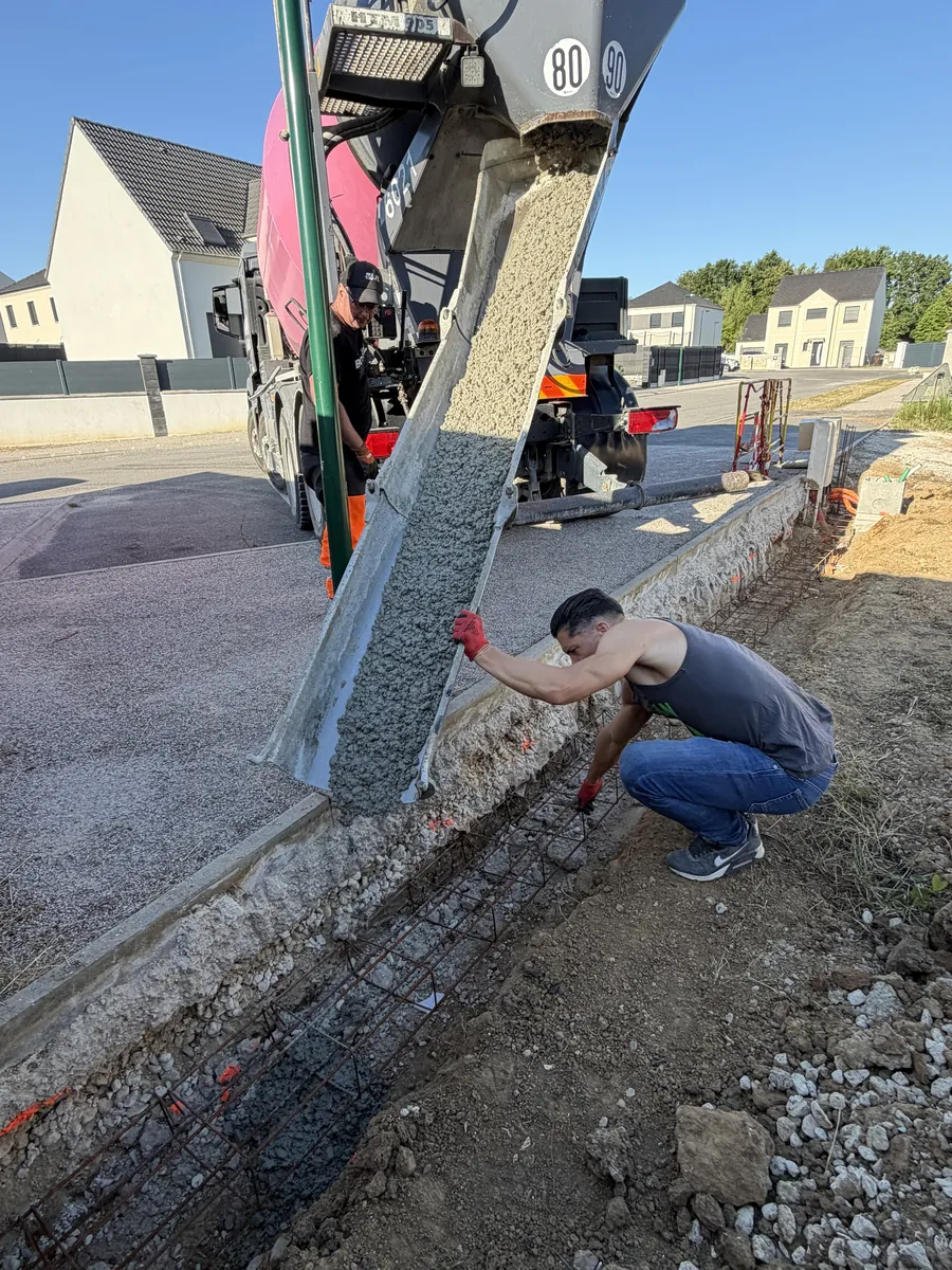 Béton coulé depuis une toupie dans la tranchée de fondation d'un muret