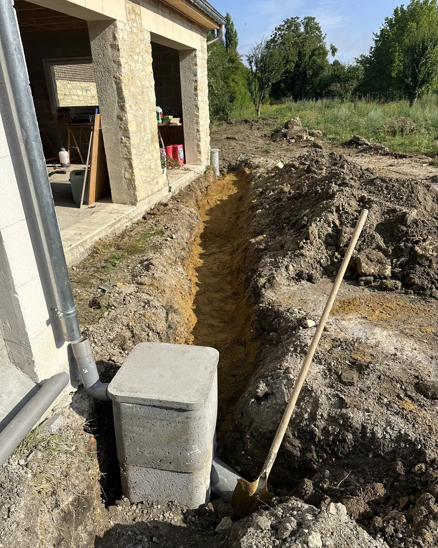 Regard en béton au pied d'une descente de gouttière, et la tranchée qui part vers le puisard