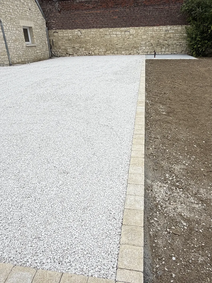Ligne de pavés entre un stationnement en gravillon blanc et la terre